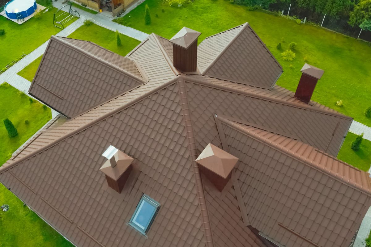 Aerial view of a house featuring brown roofing, showcasing the work of a roofing service.