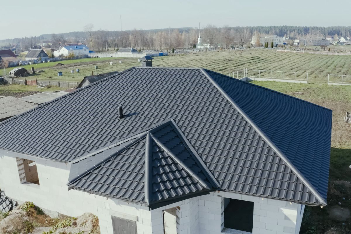 A house featuring a black roof on one side and a white roof on the other, representing a roofing service's work.