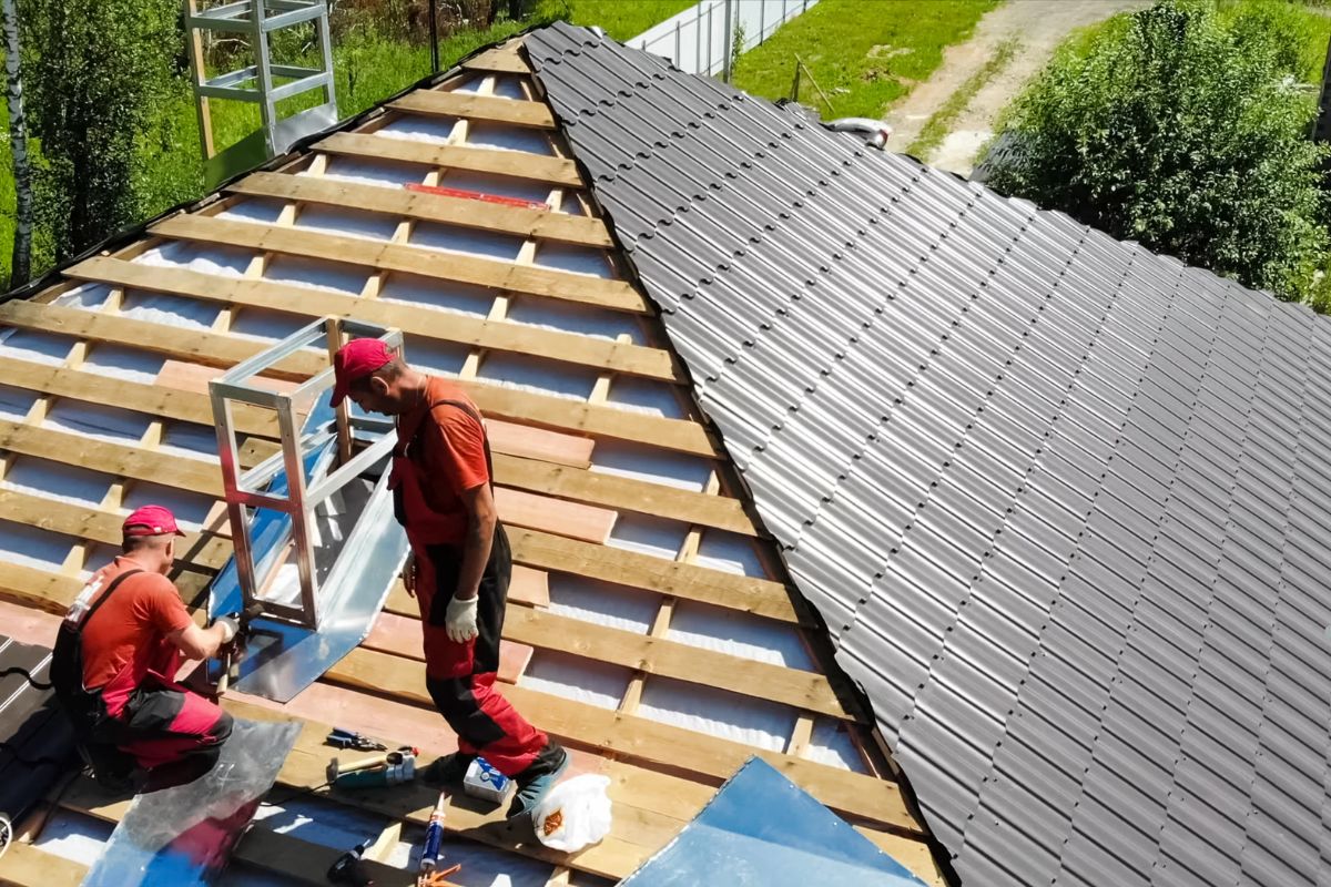 Two men installing a metal roof as part of a roofing service, working diligently on a residential building.