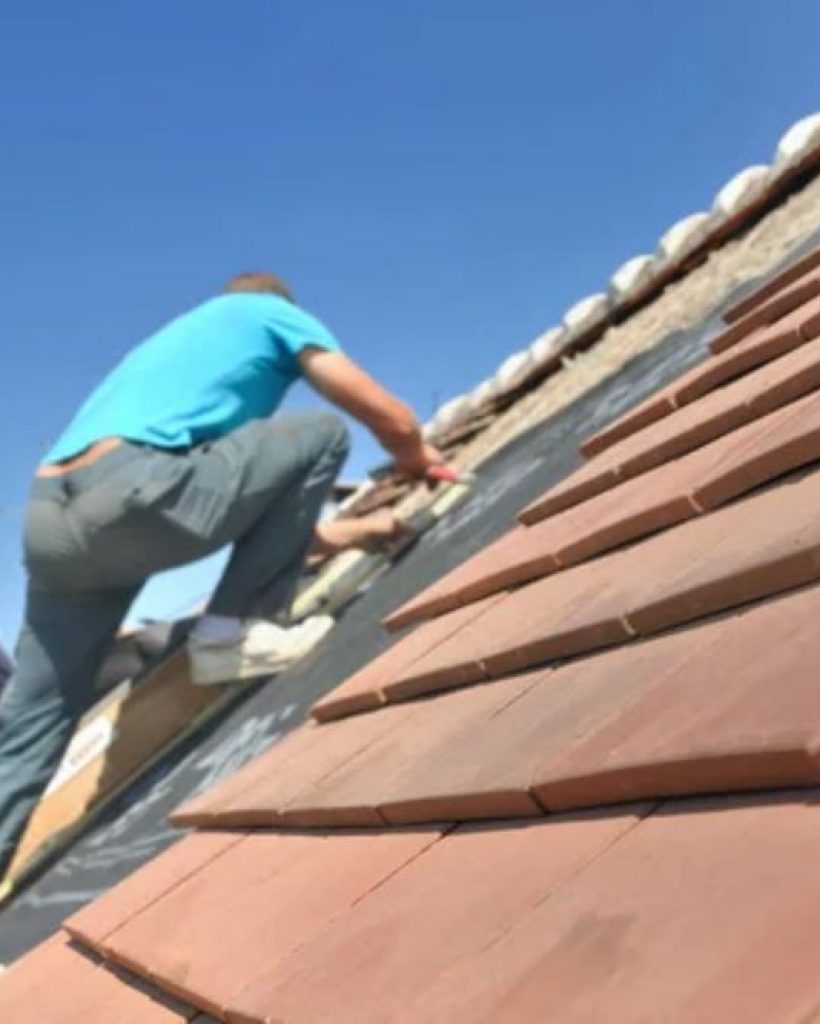 A worker is engaged in roof maintenance on a tiled surface, representing our services in Reno, NV.